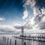Blue Sky Grey Clouds Red White Lighthouse Wooden Pier Water background image & Google Slides Theme