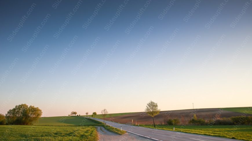 Gradient blue sky green fields road background image