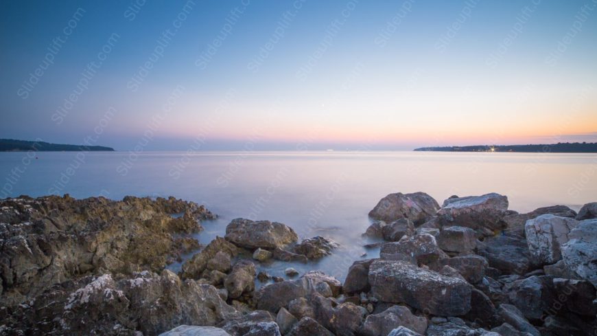 Pale Blue Pink Sky Rocks Shoreline background image