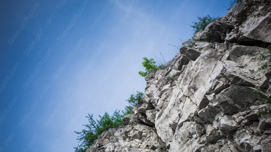 Pale Blue Sky Grey Rock Formation Green Foliage background image