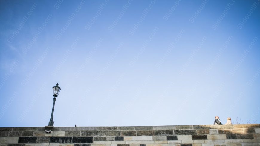 Sky Blue Lamp Post and Persons Stone Wall background image