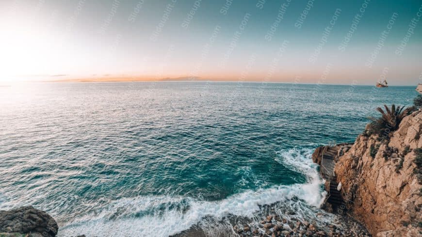 Blue Sea and Sky Orange Horizon Ship Rocky Cliff background image