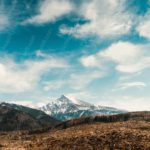 Blue Sky White Clouds Brown Mountain Green Trees background image & Google Slides Theme