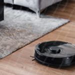 Black Robotic Vacuum Cleaner Wood And Carpet Background Image & Google Slides Theme