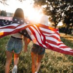 Red White Blue Flag Two People Sunset Grass Background Image & Google Slides Theme